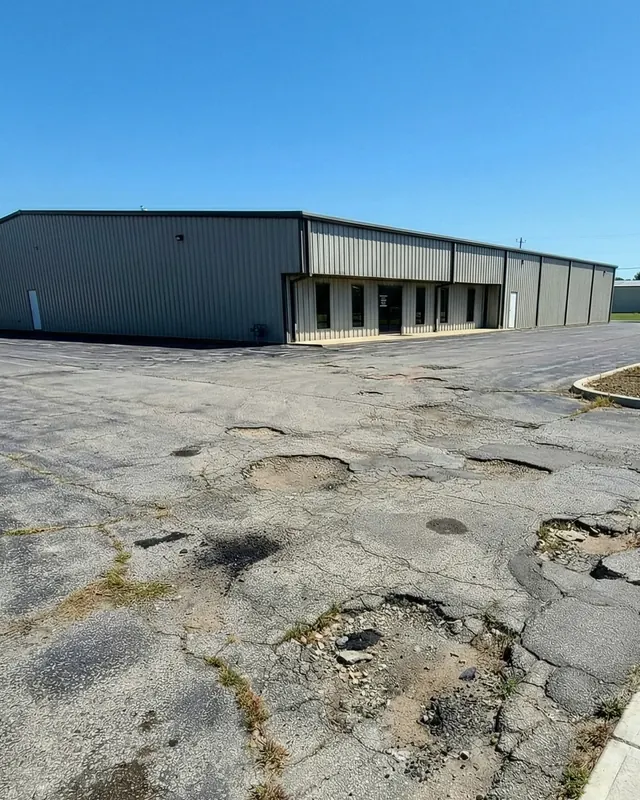 Potholed, crumbling commercial parking lot before paving