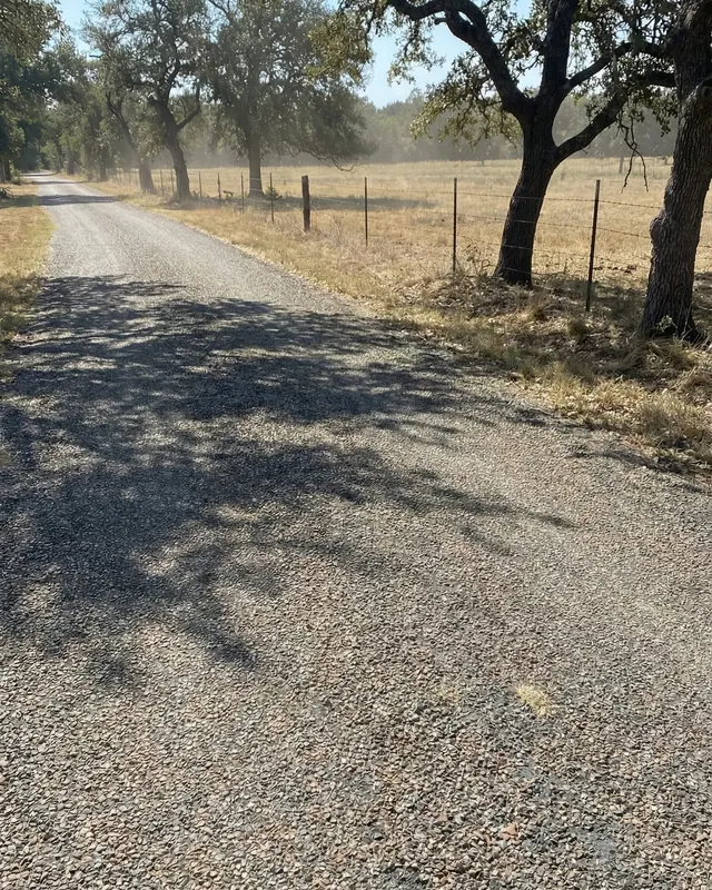 The same ranch road resurfaced with a smooth stone surface under live oaks